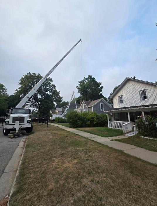 Crane truck reaching over a two-story home for a residential removal